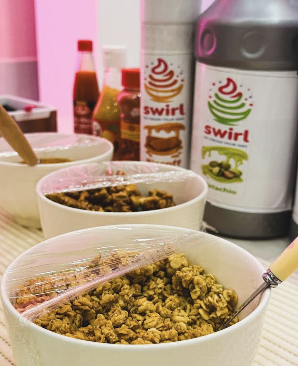 Bowls of granola next to Swirl sauce bottles